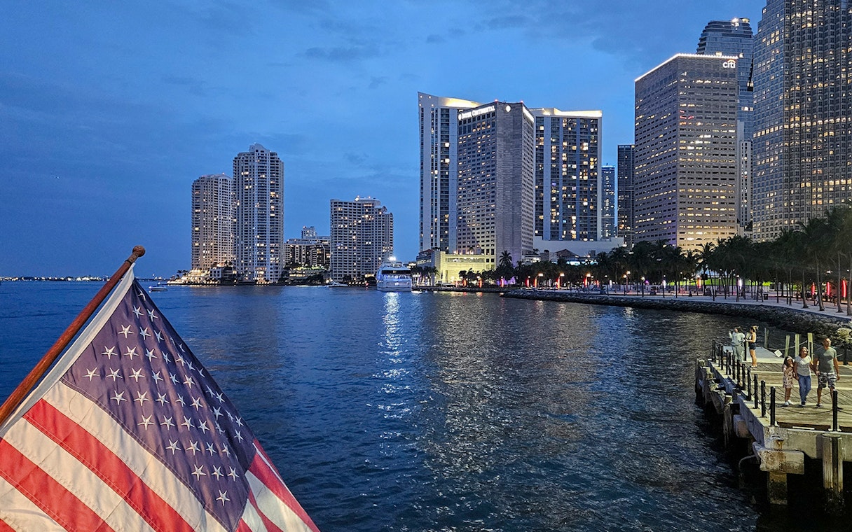 Sunset view of Biscayne Bay with Miami skyline and American flag on a cruise.
