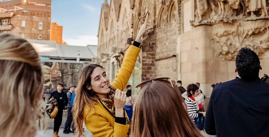 Guide leading a tour group at Sagrada Familia, pointing at architectural details.