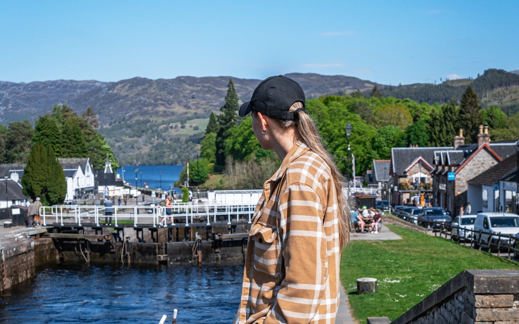 Tourist observing canal locks at Fort Augustus, Scotland with hills in the background.