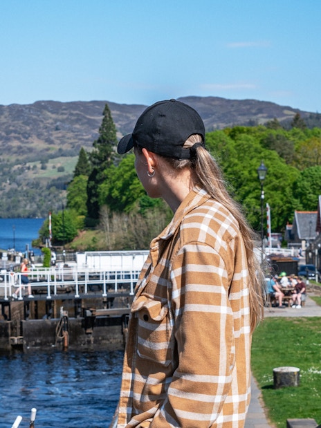 Tourist observing canal locks at Fort Augustus, Scotland with hills in the background.