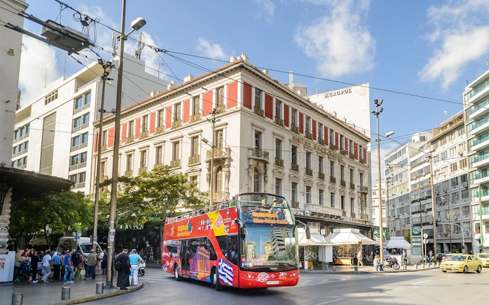 HOHO tour bus in central Athens near historic buildings.