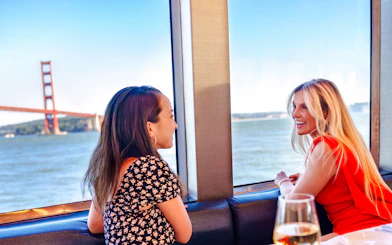 Two women enjoying a view of the Golden Gate Bridge from a San Francisco dinner cruise.