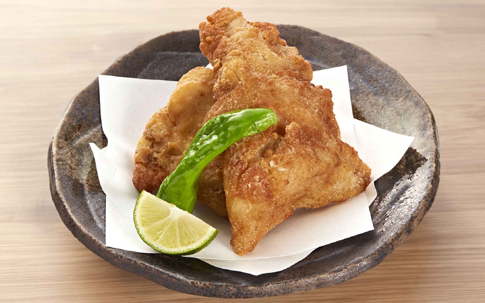 Fried puffer fish with lime and pepper on a plate at Torafugu-tei Ginza.