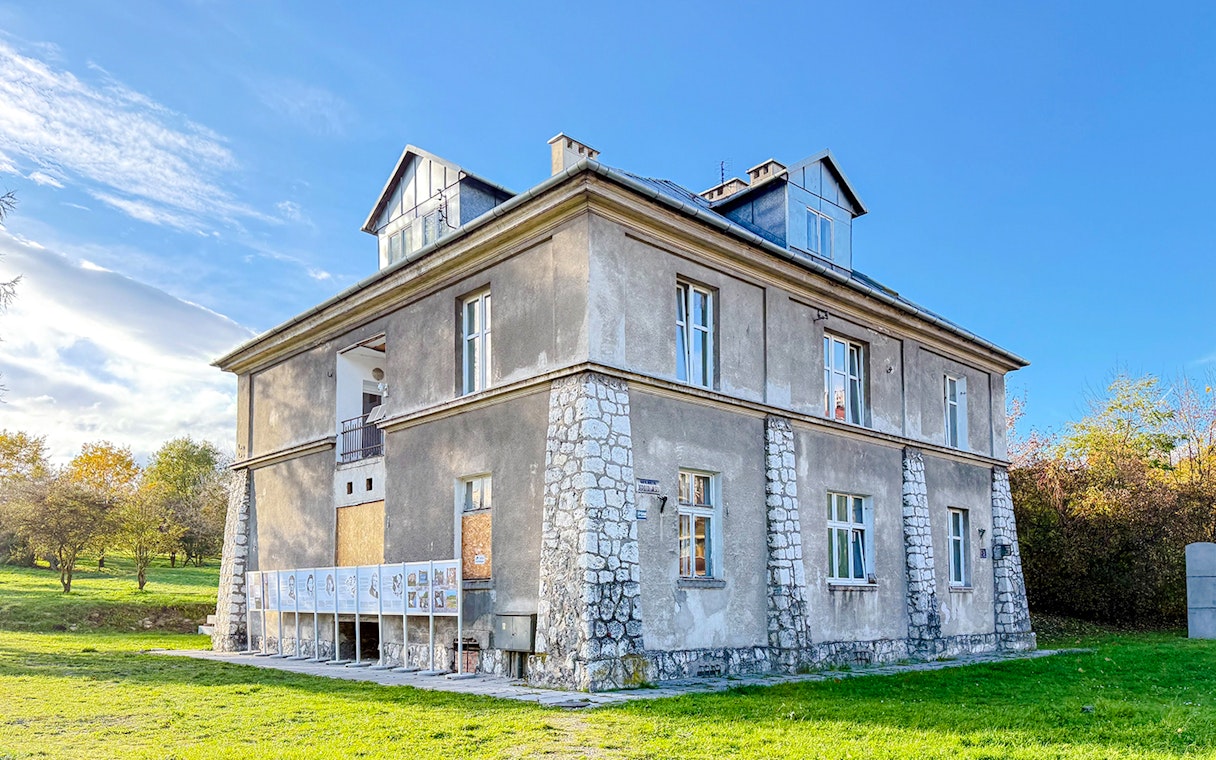 Historic building at Płaszów Concentration Camp site, Kraków, surrounded by greenery.