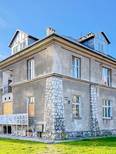 Historic building at Płaszów Concentration Camp site, Kraków, surrounded by greenery.