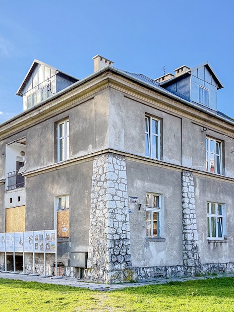 Historic building at Płaszów Concentration Camp site, Kraków, surrounded by greenery.