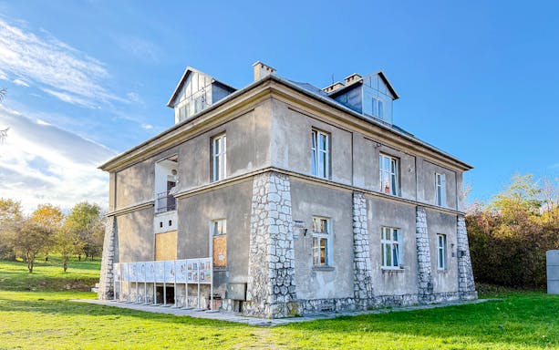 Historic building at Płaszów Concentration Camp site, Kraków, surrounded by greenery.