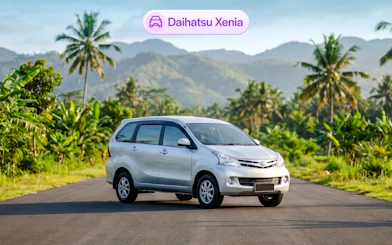 Daihatsu Xenia parked on a scenic road in Bali with palm trees and mountains.