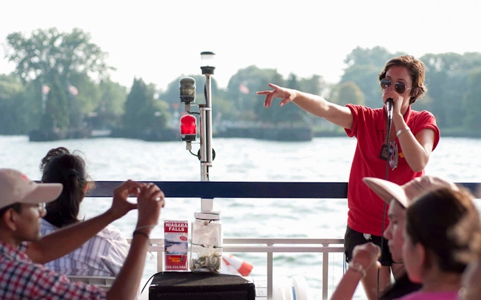 Tour guide speaking to passengers on a Toronto Harbour cruise with islands in the background.
