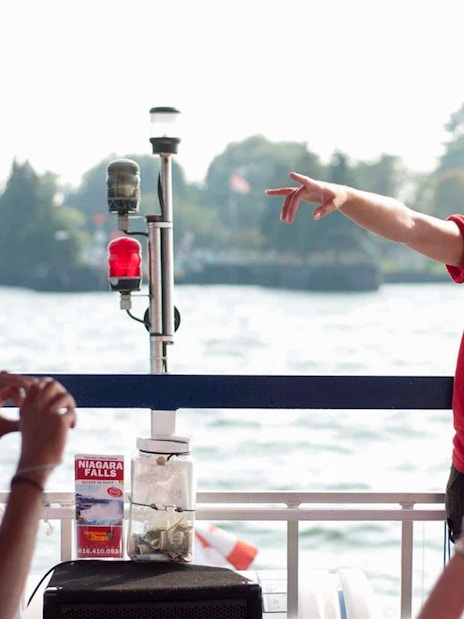 Tour guide speaking to passengers on a Toronto Harbour cruise with islands in the background.