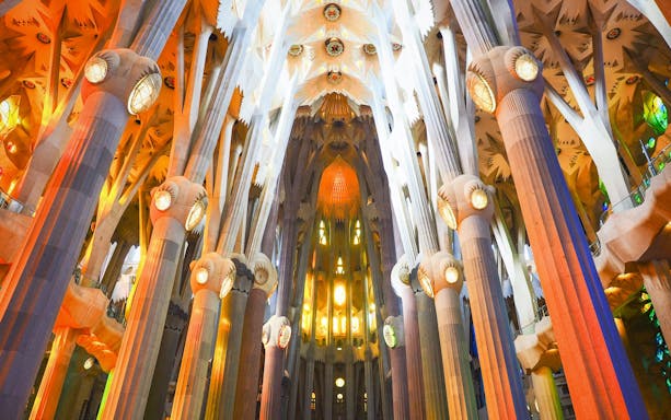 Sagrada Familia interior with illuminated columns and intricate ceiling design.