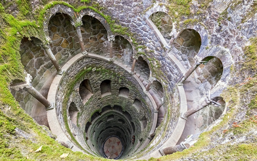Tour group exploring the spiral staircase of the Initiation Well at Quinta da Regaleira, Sintra, Portugal.