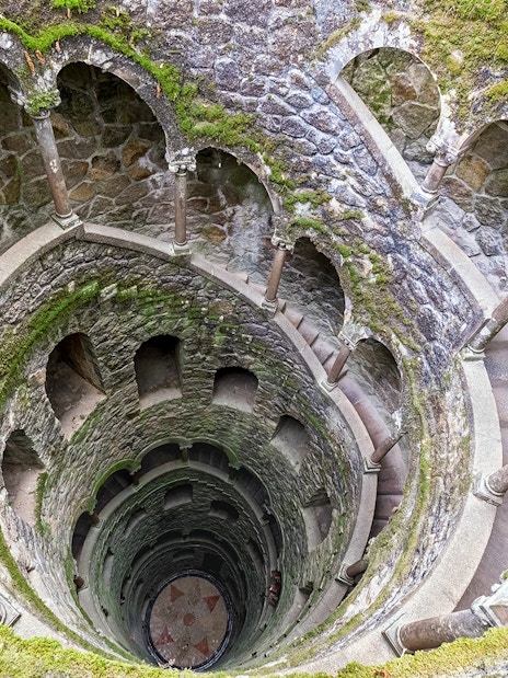 Tour group exploring the spiral staircase of the Initiation Well at Quinta da Regaleira, Sintra, Portugal.