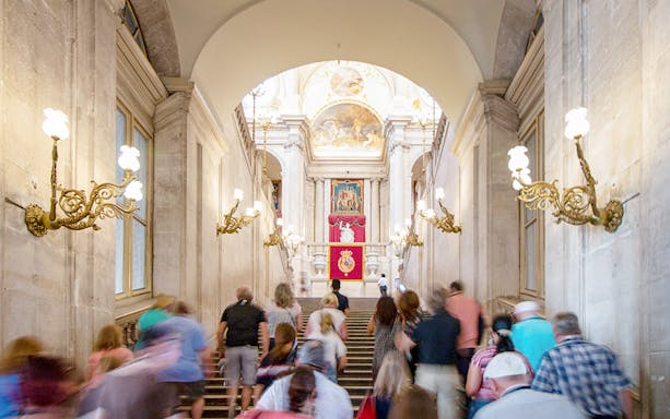 Participants ascending staircase in Royal Palace of Madrid during guided tour with priority access.