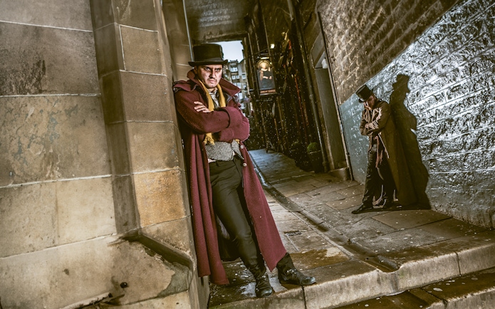 Victorian characters in a dimly lit alley at Edinburgh Dungeon.