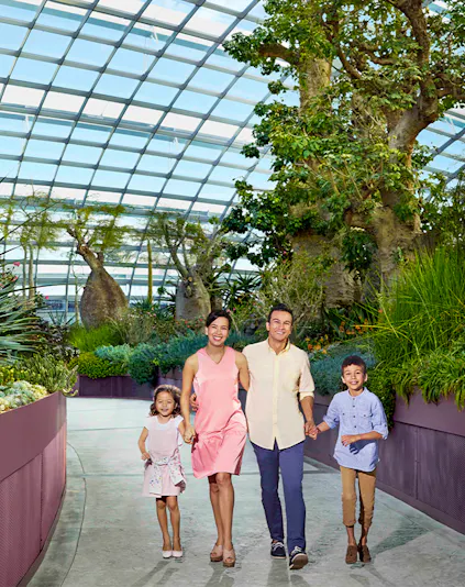 Family walking in Singapore's Gardens by the Bay conservatory, surrounded by lush greenery.