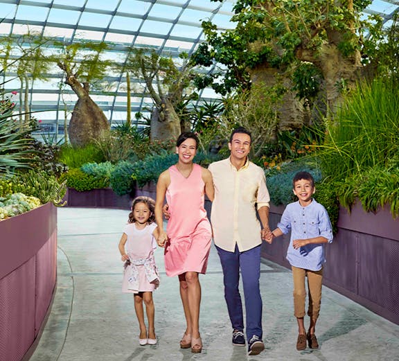 Family walking in Singapore's Gardens by the Bay conservatory, surrounded by lush greenery.