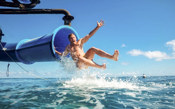 Man sliding from boat into ocean water.