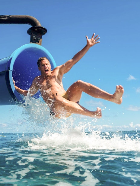 Man sliding from boat into ocean water.