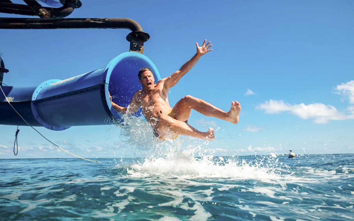 Man sliding from boat into ocean water.