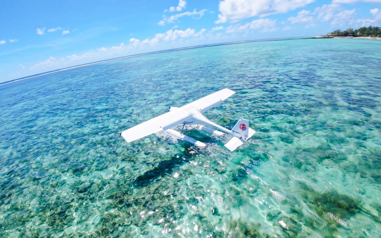 Seaplane flying over clear turquoise waters on the Eastern Underwater Waterfall route, Mauritius.