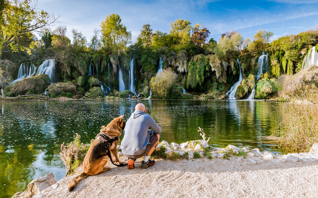 Man with dog by Kravica waterfall in Bosnia.