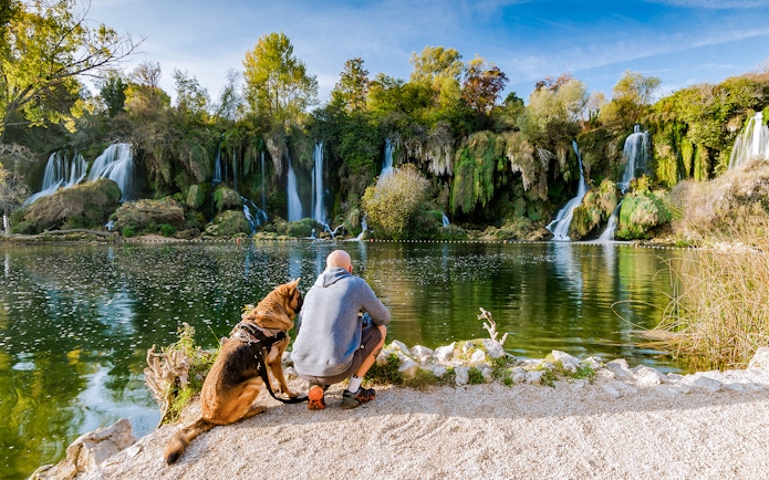 Man with dog by Kravica waterfall in Bosnia.