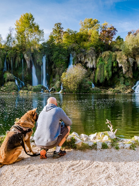 Man with dog by Kravica waterfall in Bosnia.