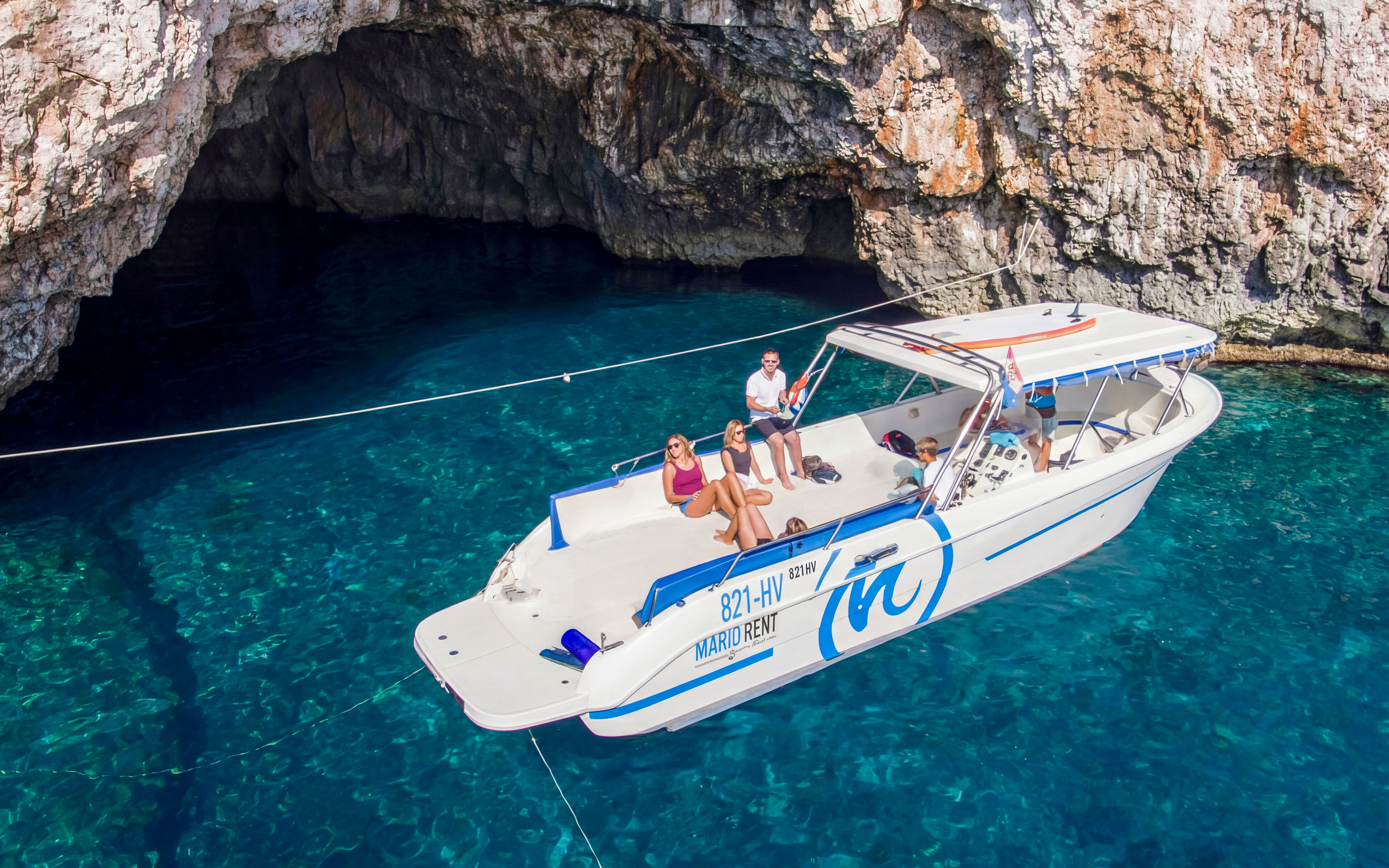 Boat tour approaching Green Cave, Croatia with passengers enjoying the view.