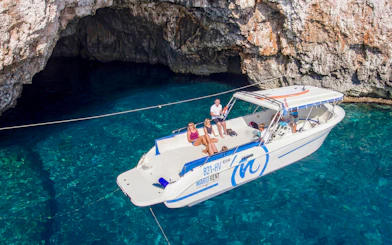 Boat tour approaching Green Cave, Croatia with passengers enjoying the view.
