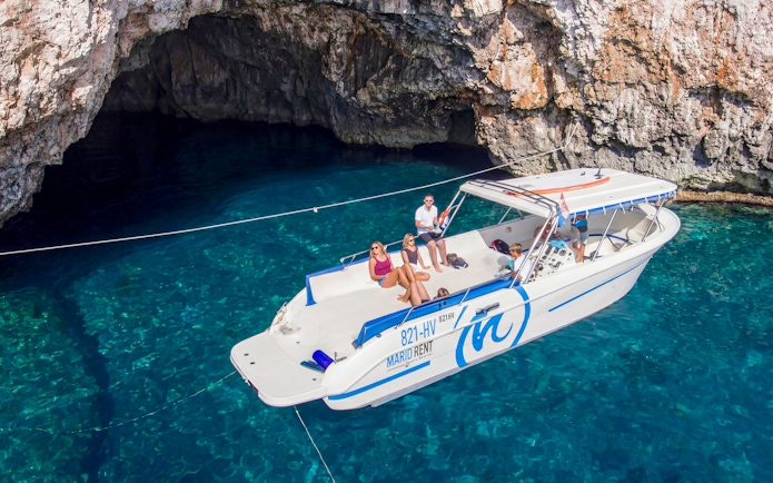 Boat tour approaching Green Cave, Croatia with passengers enjoying the view.