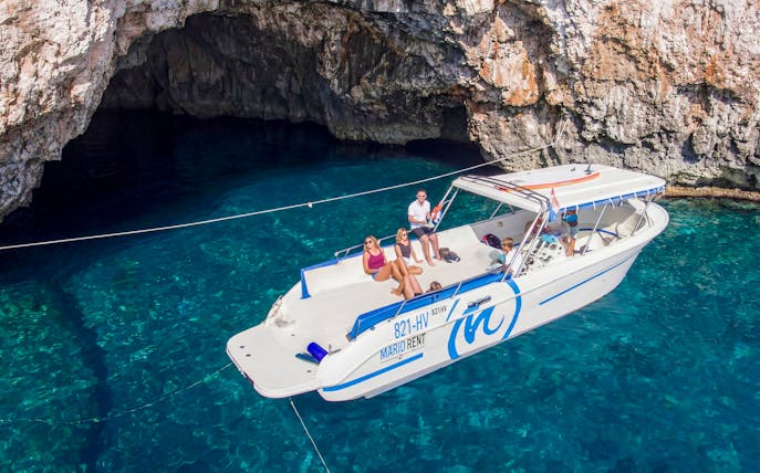Boat tour approaching Green Cave, Croatia with passengers enjoying the view.