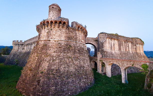 Fortezza di Sarzanello at dusk with stone walls and towers in Sarzana, Italy.