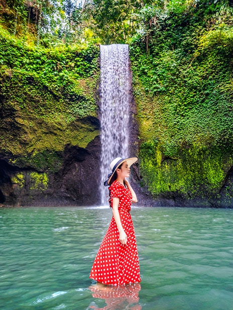 Woman standing in front of Tibumana Waterfall, Bali, Indonesia.