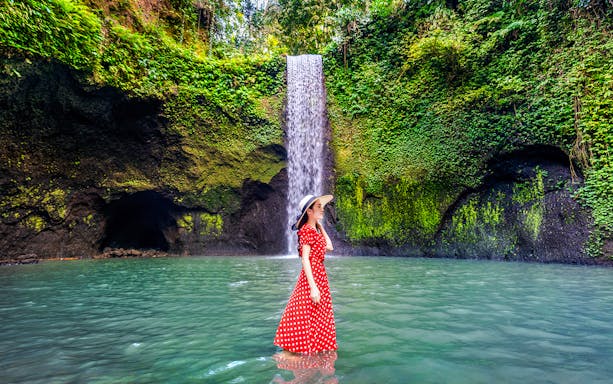 Woman standing in front of Tibumana Waterfall, Bali, Indonesia.