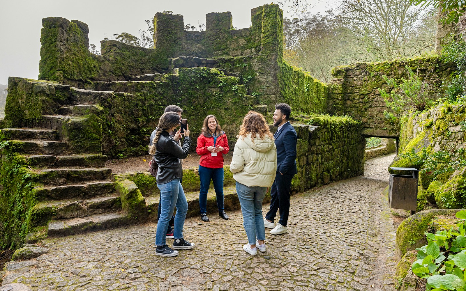Tourists with guide exploring Moorish Castle, Sintra, Portugal, highlighting historical architecture.