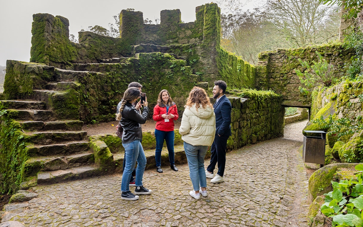 Tourists with guide exploring Moorish Castle, Sintra, Portugal, highlighting historical architecture.