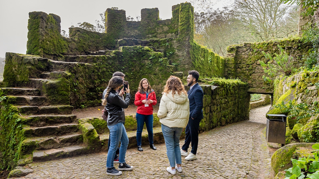 Tourists with guide exploring Moorish Castle, Sintra, Portugal, highlighting historical architecture.