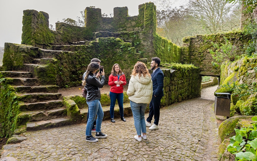 Tourists with guide exploring Moorish Castle, Sintra, Portugal, highlighting historical architecture.