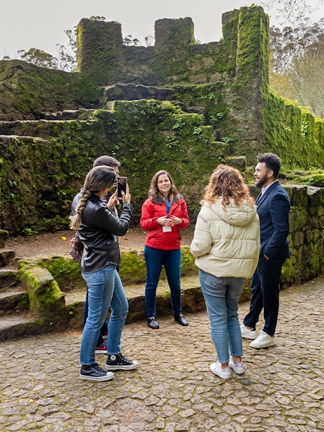 Tourists with guide exploring Moorish Castle, Sintra, Portugal, highlighting historical architecture.