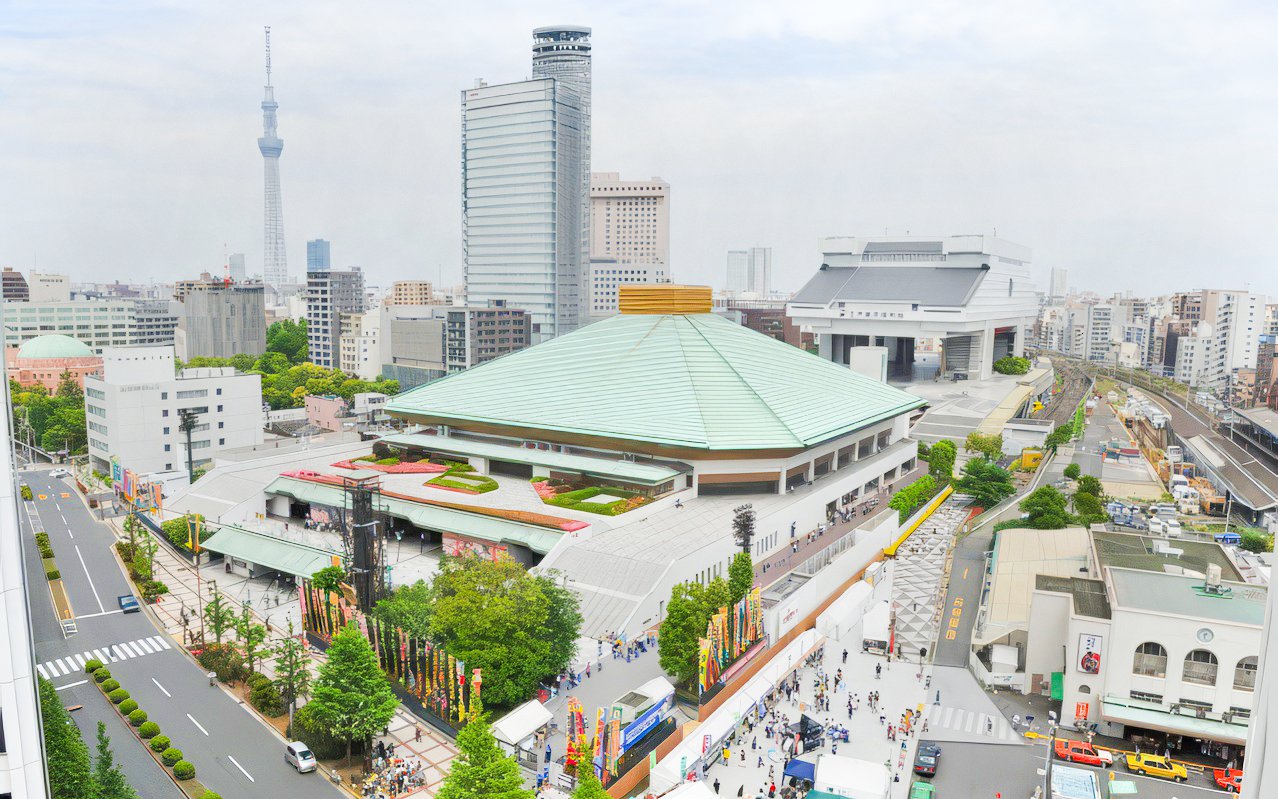 Sumo wrestling arena in Tokyo with surrounding cityscape and Tokyo Skytree in the background.