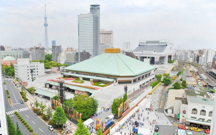 Sumo wrestling arena in Tokyo with surrounding cityscape and Tokyo Skytree in the background.