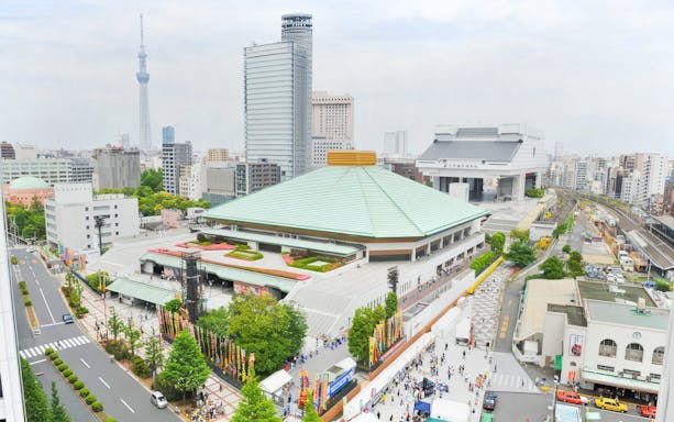 Sumo wrestling arena in Tokyo with surrounding cityscape and Tokyo Skytree in the background.