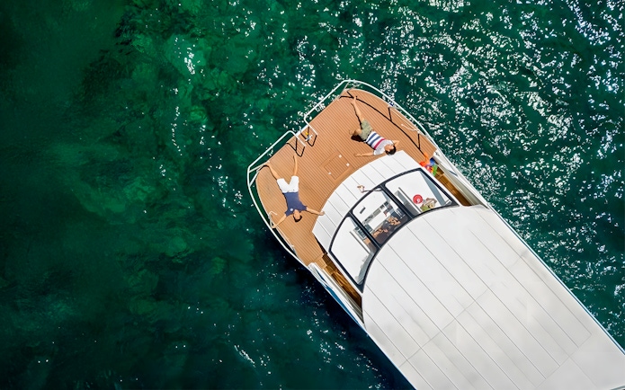 Two people sunbathing on a boat in turquoise waters, Phi Phi, Thailand.