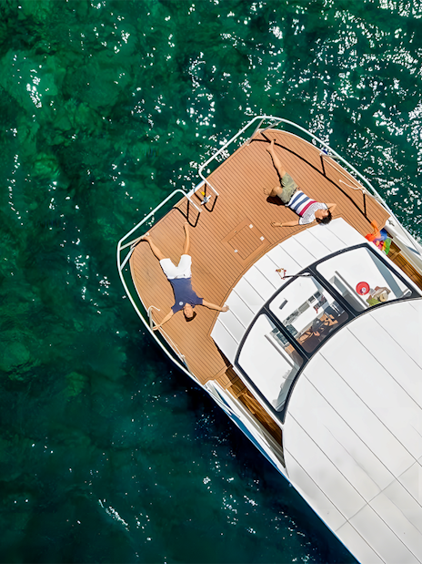 Two people sunbathing on a boat in turquoise waters, Phi Phi, Thailand.