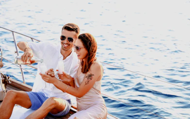 Couple enjoying wine on a sailboat with ocean view.