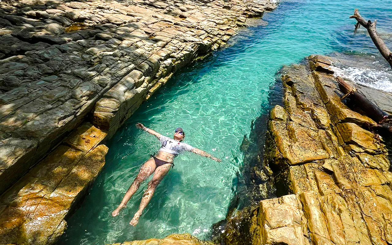 Person floating in clear water between rocky formations, Archipiélago de las Perlas, Panama.