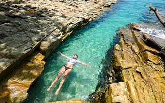 Person floating in clear water between rocky formations, Archipiélago de las Perlas, Panama.