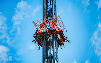 Visitors on the Screaming Eagle ride at Bellewaerde Park, ascending against a clear blue sky.