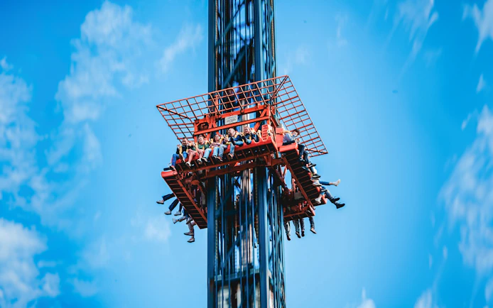 Visitors on the Screaming Eagle ride at Bellewaerde Park, ascending against a clear blue sky.
